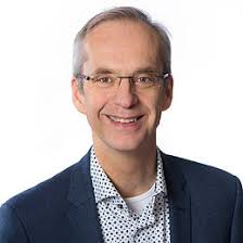 photo of smiling man, wearing a blazer and button down shirt