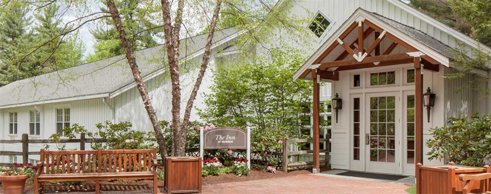 Front of Warren Conference Center building, front door is glass with windows on either side, there are trees and flowers along the front walk