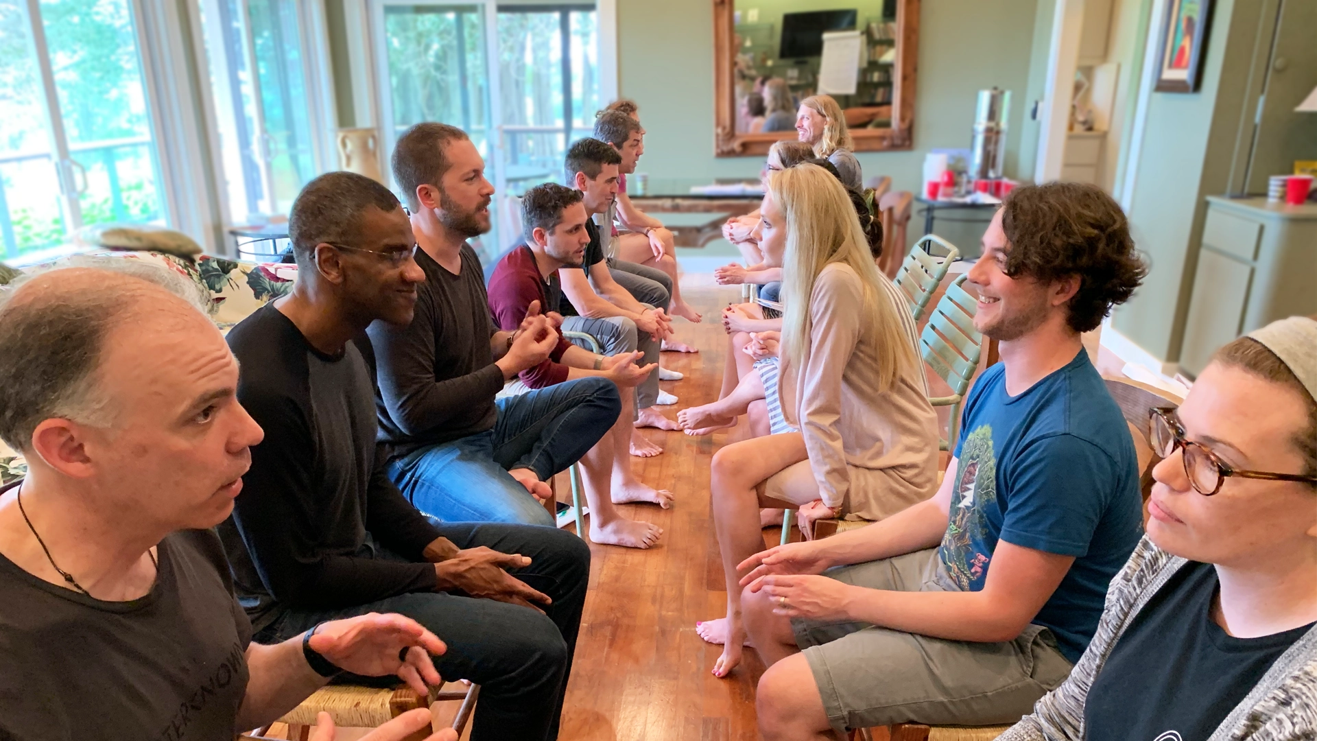 Students sitting in two rows, facing each other and talking to the person across from them. All are casually dressed and fully engaged with their partner.