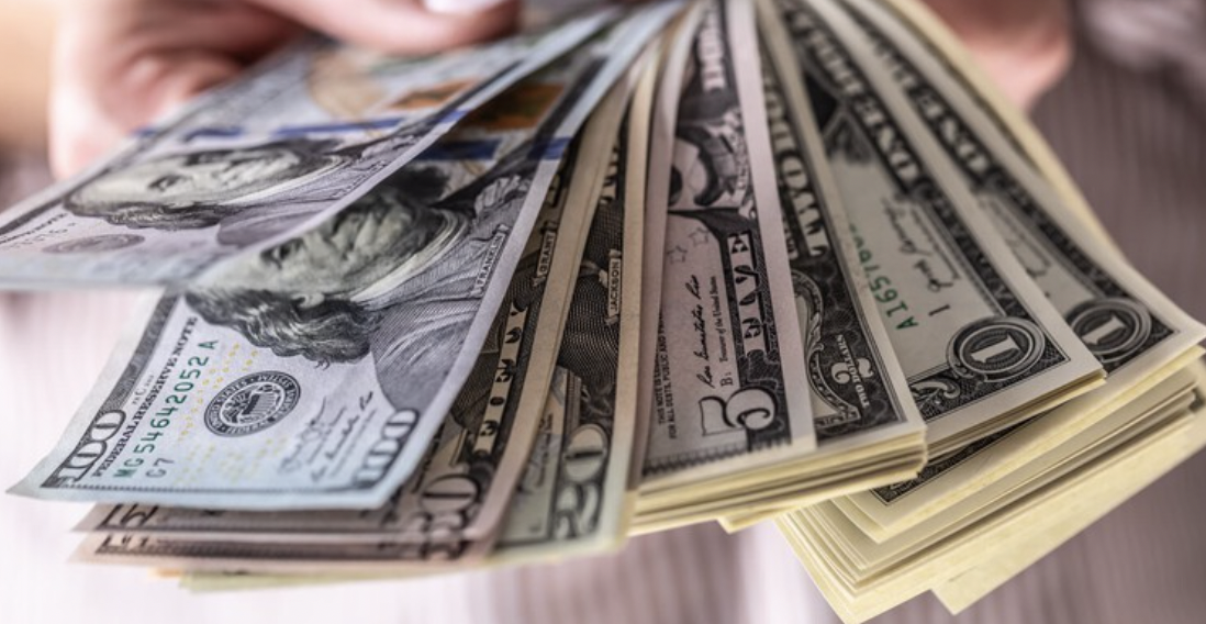 A close up photo of hands displaying cash.